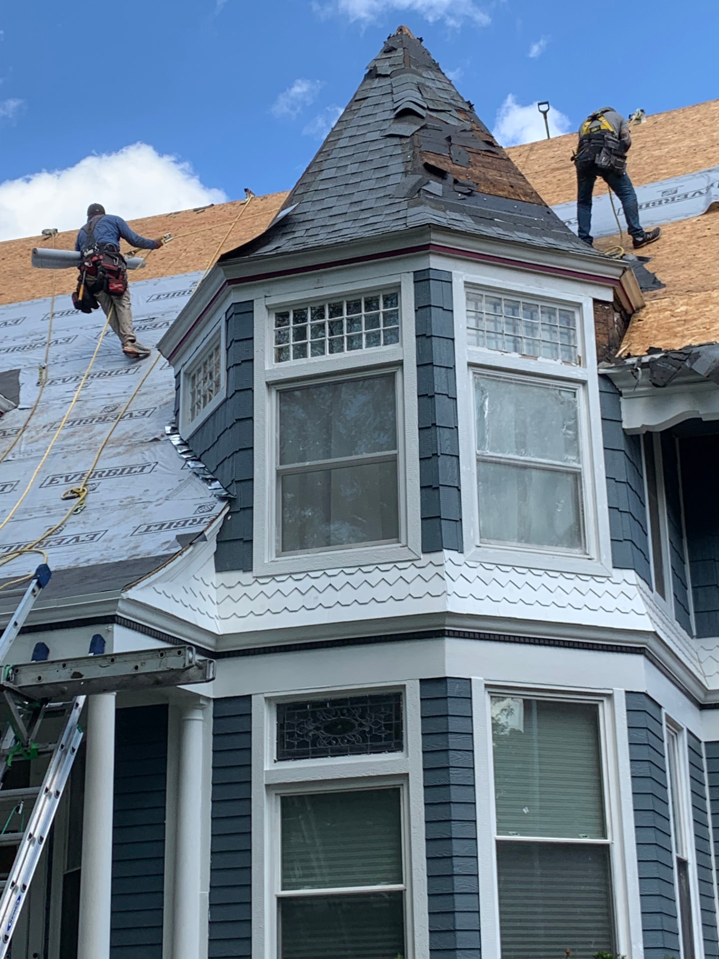 Roofing crew replacing decking and underlayment on a Victorian home